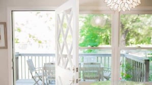 Porta aperta che dà su un balcone con sedute all'aperto e vista sul verde.
