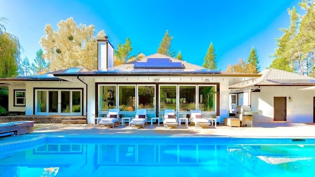 Una casa moderna con piscina, ampie finestre e una veranda coperta.