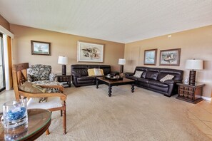 A living room with two leather sofas, a wooden armchair, a coffee table, and a glass table with a blue object.