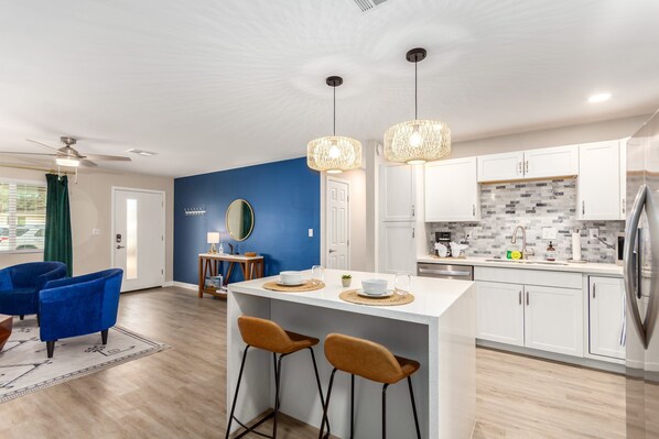 A modern kitchen with white cabinets, a central island, and pendant lighting. - Marigold Tempe (Tempe)