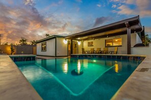 Una casa moderna con piscina, un porche cubierto e interiores bien iluminados.