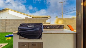 Ein Terrassenbereich mit Grillabdeckung, Billardtisch und Backsteinmauer.