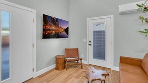 Una sala de estar moderna con un cuadro de un paisaje urbano, una silla de madera, una mesa redonda y un sofá de cuero.