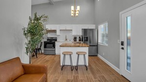 Una cocina moderna con armarios blancos, electrodomésticos de acero inoxidable y una isla de madera con taburetes de bar.