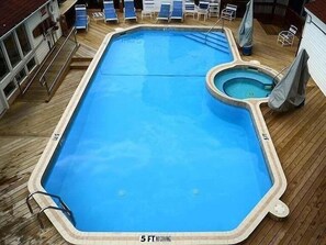 A rectangular swimming pool with a smaller circular hot tub, surrounded by wooden decking and lounge chairs. - Million Dollar Bayview Beach Pool Downtown TC 1995 (Traverse City)