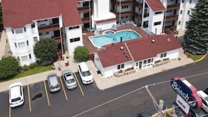Ein mehrstöckiges Hotel mit Schwimmbad, Parkplatz und Meerblick.