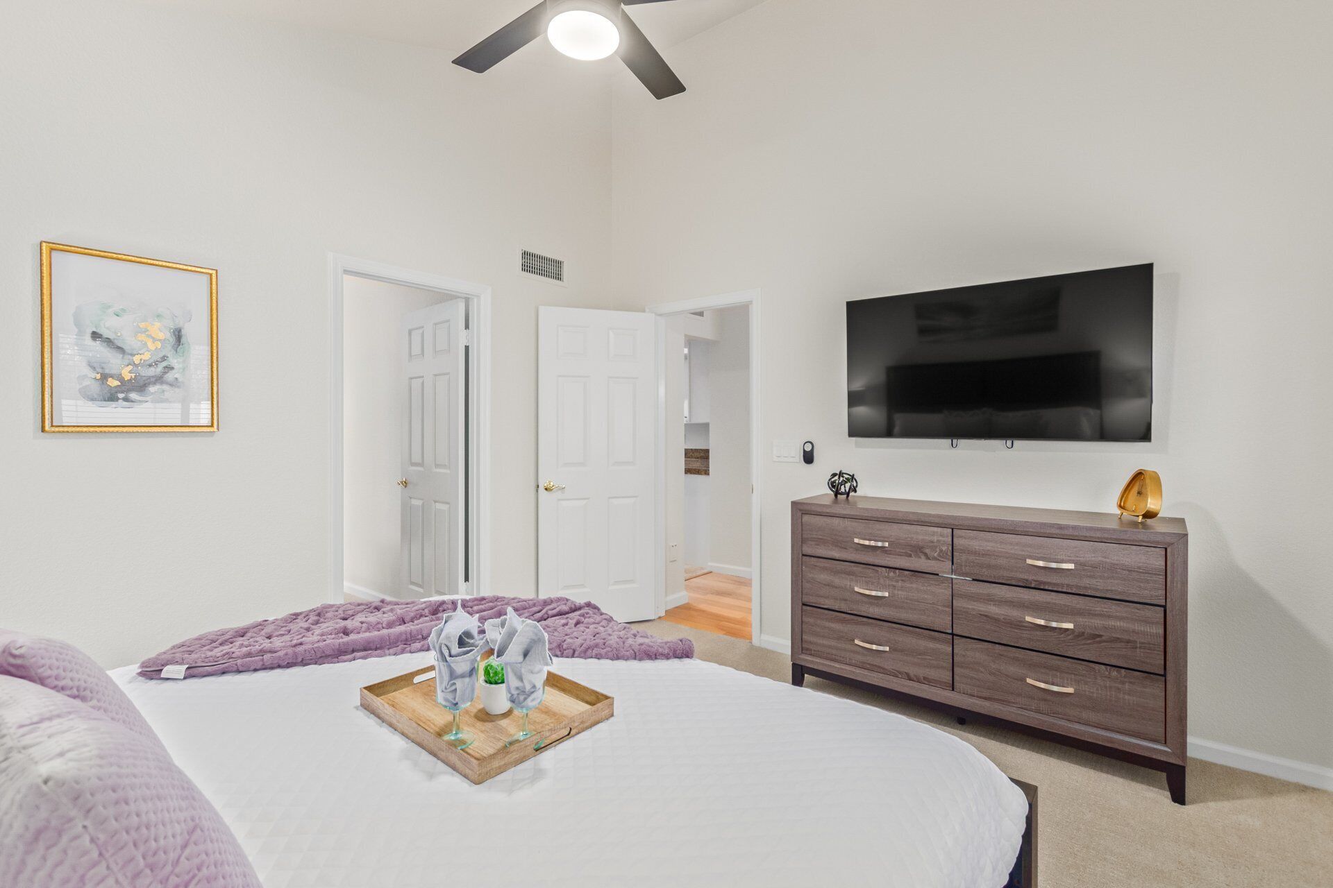 A bedroom with a bed, a dresser, a TV, and a door.