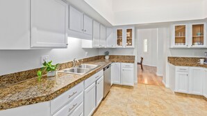 A kitchen with white cabinets, granite countertops, and a tiled floor. - Mary Katherine Scottsdale (Scottsdale)
