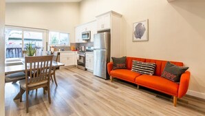 Une cuisine moderne avec des meubles blancs, des appareils en acier inoxydable et un coin repas comprenant une table et des chaises en bois.