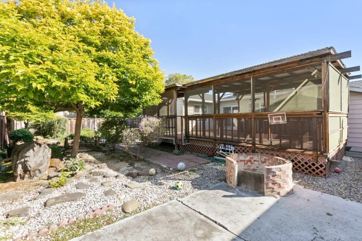 A house with a covered porch, a garden with stepping stones, and a tree.