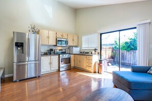 A modern kitchen with stainless steel appliances, wooden cabinets, and a large sliding glass door leading to a backyard. - Marbella Lane -siliconvalley 3BR Gem in SJ (San Jose)