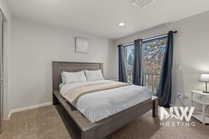 A bedroom with a bed, a nightstand, a window with curtains, and a ceiling vent. - Twin Lakes Village 3-story Townhouse Golf Views Steam Shower Wet Bar Game Room Pool (Rathdrum)