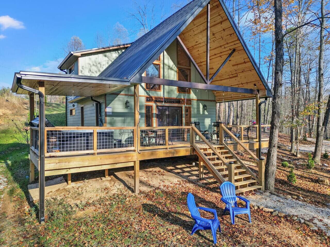 A cabin with a large deck, a covered porch, and a staircase leading to the main entrance.