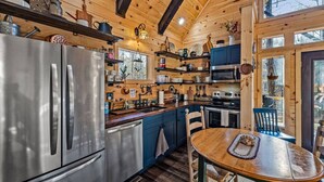 A modern kitchen with stainless steel appliances, wooden cabinets, and a dining area with a wooden table and chairs. - Wifi, Hot Tub & Pets - Eaglerock Retreat in Rrg! (Rogers)