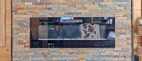 Una chimenea de piedra con puerta de cristal, incrustada en una pared de madera.
