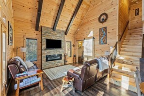 A wooden interior with a fireplace, leather sofa, and a staircase.