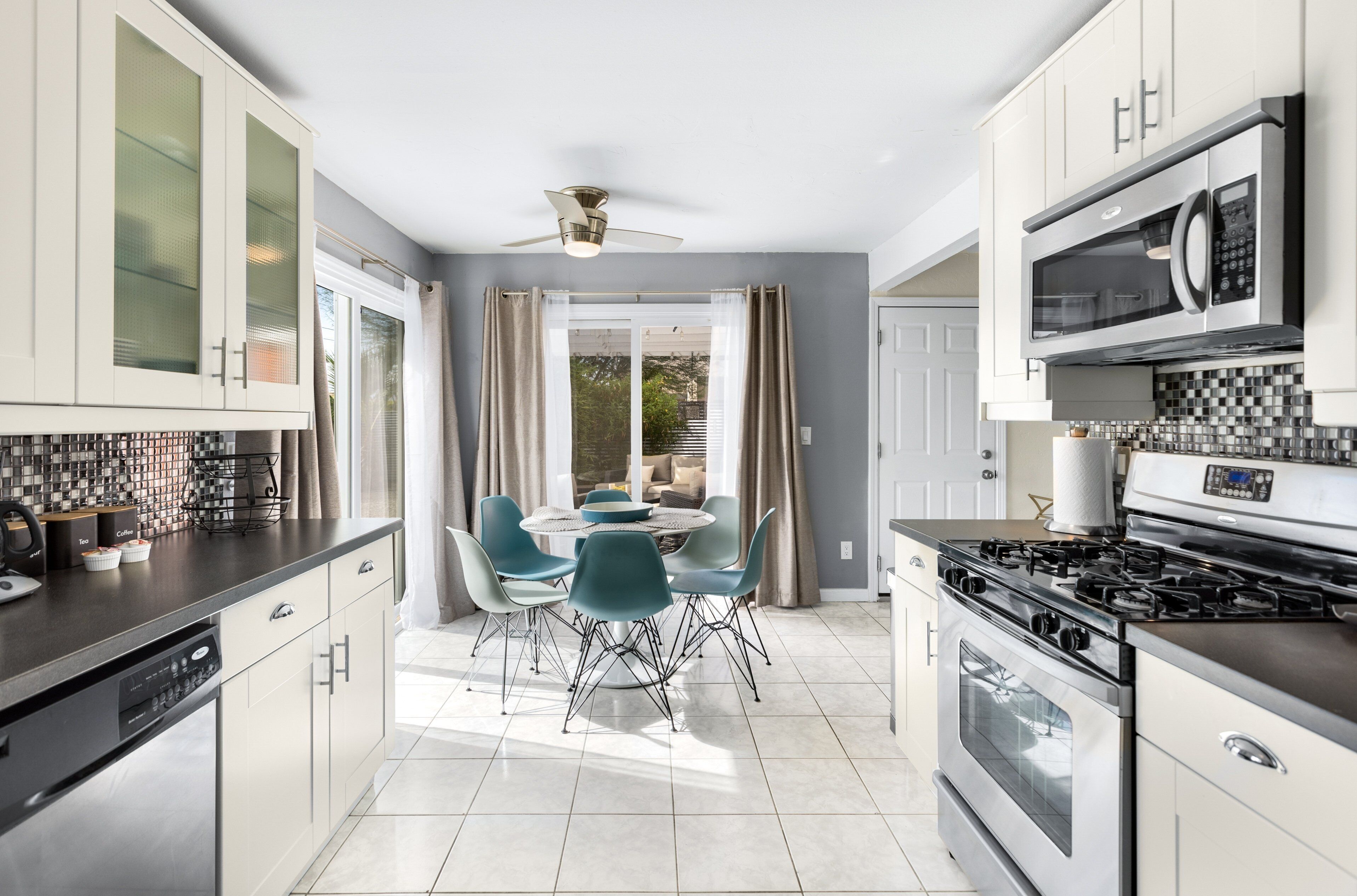 Una cucina moderna con zona pranzo, caratterizzata da elettrodomestici in acciaio inossidabile, lavastoviglie e un tavolo rotondo con sedie.