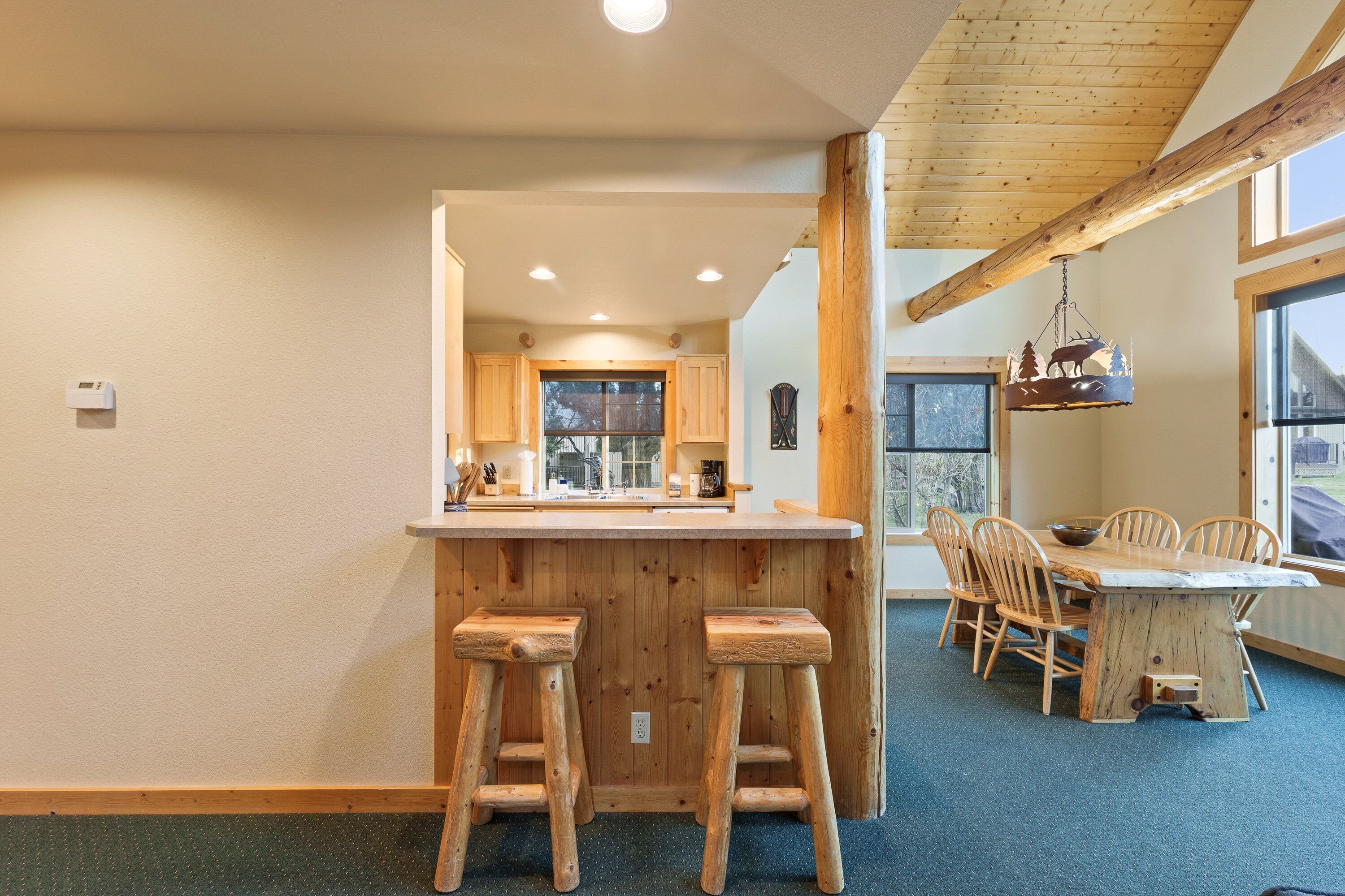 A kitchen with wooden stools, a wooden dining table, and a view through the window.