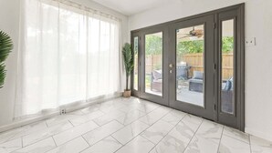A room with a sliding glass door leading to a patio, a potted plant, and a tiled floor.