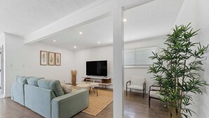 A living room with a sofa, TV, and a potted plant.