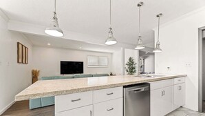 A modern kitchen with white cabinetry, a granite countertop, and pendant lighting.