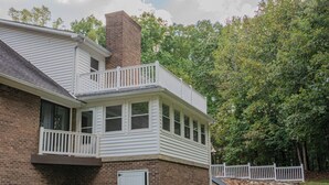 Een tweelaags huis met een balkon, een stenen muur en een gazon.