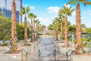 A pathway lined with palm trees and planters, leading to a building with a glass facade. - Spacious MGM Studio Topgolf Pool Views 07718 (Las Vegas)