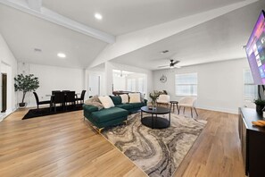 A spacious living area with a sectional sofa, a dining table, and a TV. - Spacious 6 Bed House Airport Pet Friendly AFB (San Antonio)