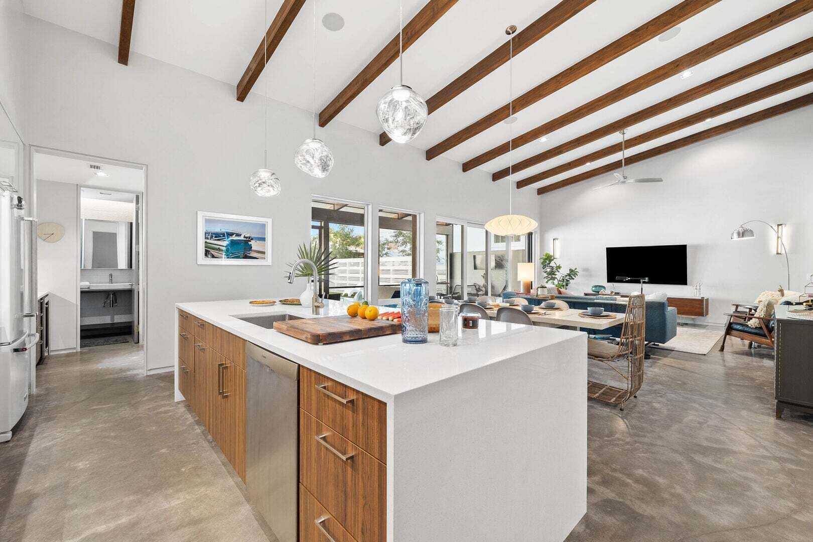 A modern kitchen with a large island, wooden cabinets, and pendant lighting.