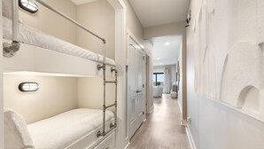 A narrow hallway with bunk beds on one side and a door leading to a balcony. - Sea Palms (Santa Rosa Beach)