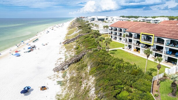 A beachfront hotel with a white building, a sandy beach, and a clear view of the ocean. - Sea Palms (Santa Rosa Beach)