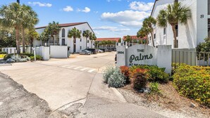 A gated entrance to a building with a sign reading "The Palms at Seaside Village." - Sea Palms (Santa Rosa Beach)