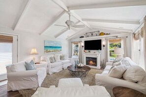 A spacious living room with a fireplace, white furniture, and a ceiling fan. - Private Backyard Oasis With Heated Pool, 4 BR, Bikes & Pond (Santa Rosa Beach)