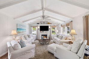 A spacious living room with white furniture, a fireplace, and a ceiling fan. - Private Backyard Oasis With Heated Pool, 4 BR, Bikes & Pond (Santa Rosa Beach)