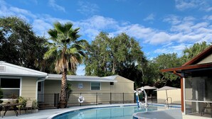 A swimming pool with a lifeguard chair, a no diving sign, and a covered area with umbrellas. - Siesta Heron 3 (Siesta Key)
