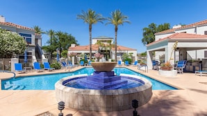 Un área de piscina con hidromasaje, sillas de descanso y palmeras.
