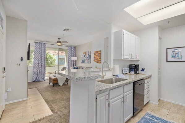 A modern kitchen with white cabinets, a granite countertop, and a built-in dishwasher. - Sahuaro #2035 Scottsdale (Scottsdale)