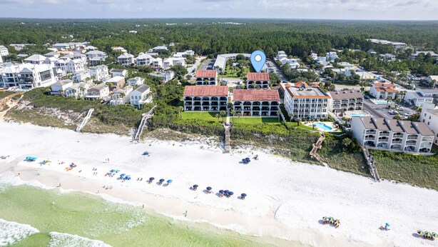 Luftaufnahme einer Küstenstadt mit Strand, einem großen Hotelkomplex und umliegenden Wohngebieten.