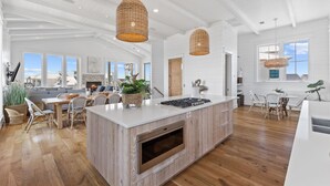 A spacious kitchen with a large island, wooden flooring, and pendant lights. - Salt & Light (Santa Rosa Beach)