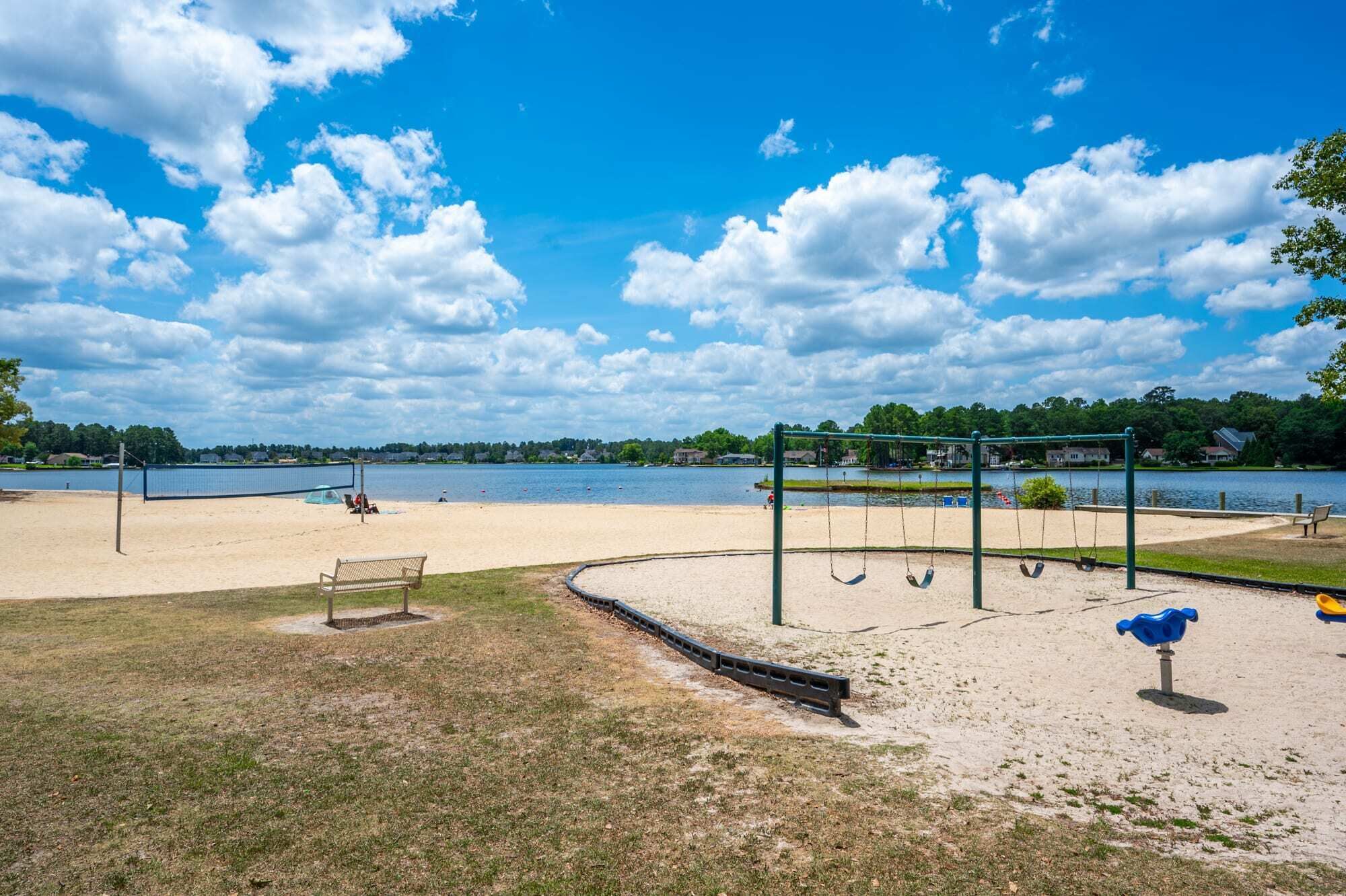 Een strandvolleybalveld met een net, schommels en een bank.