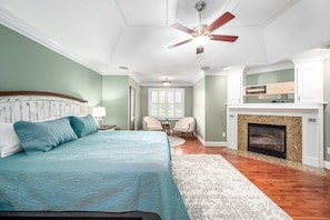 A bedroom with a bed, a ceiling fan, a fireplace, and a dining area with chairs. - Private Pool! Wateredge Lake House (Sanford)
