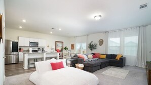 Eine moderne Wohnung mit Küche, Essbereich und Wohnzimmer. Sie beinhaltet ein Bett, ein Schlafsofa und einen Couchtisch.