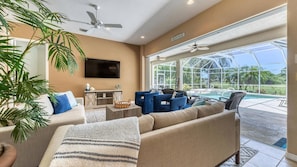 A spacious living room with a large window overlooking a pool and a view of the outdoors. - Rtc974 (Rotonda West)
