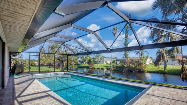 Une piscine offrant une vue dégagée sur un lac et des palmiers en arrière-plan.