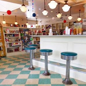 A diner with checkered flooring, bar stools, and a counter with various items. - Tranquil Oasis Golf Course Views Near Beach 1809 (Seabrook Island)