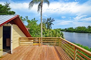 Une terrasse en bois avec une balustrade, un bâtiment avec un toit rouge et une vue sur la rivière.