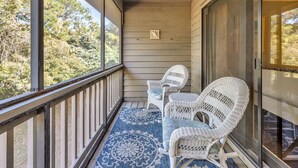A covered porch with two wicker chairs and a blue patterned rug. - Somewhere in the Sun (Santa Rosa Beach)