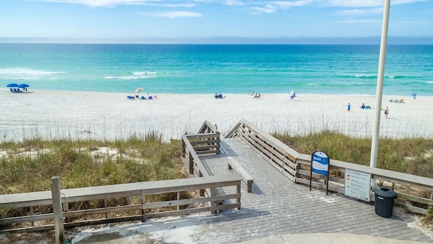 A wooden boardwalk leading to a sandy beach with clear blue water. - Somewhere in the Sun (Santa Rosa Beach)