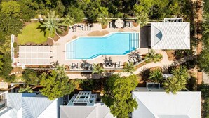An aerial view of a resort with a swimming pool, lounge areas, and surrounding greenery. - Om Sweet Om (Santa Rosa Beach)