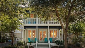 A two-story house with a balcony, a porch with chairs, and a number '21' on the door. - Om Sweet Om (Santa Rosa Beach)